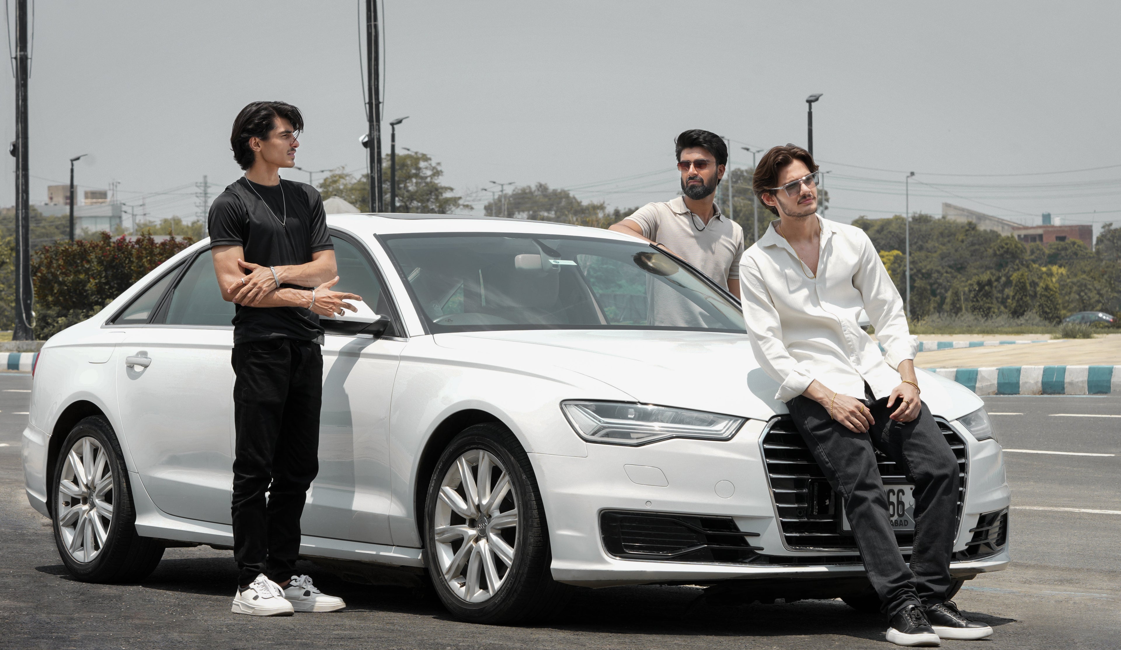 Three people standing next to a white Audi car on a track.